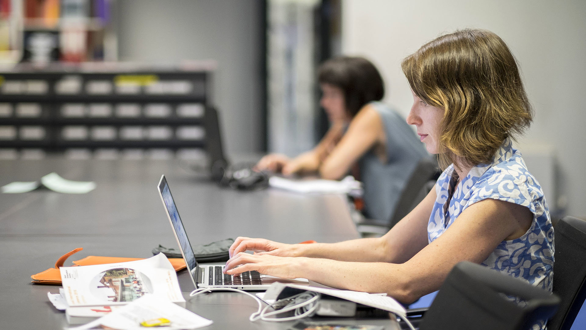 Person at a large table typing on a laptop.