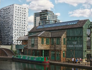Old and new building side by side in an urban area, with a canal boat in the foreground