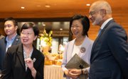 Two smiling women and a man in formal wear attending a work conference.