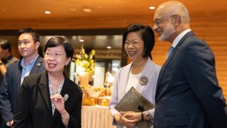 Two smiling women and a man in formal wear attending a work conference.