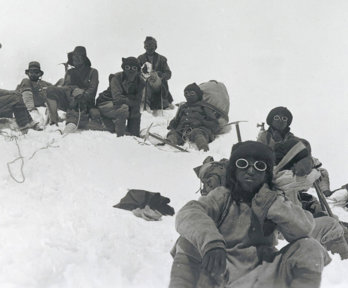 Historic black and white photograph of Sherpa climbers with mountaineering equipment on Mount Everest.