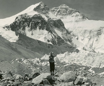 Old black and white photograph of a person taking a picture of Mount Everest.