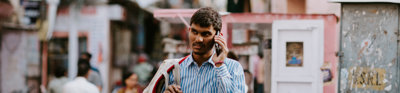 A man walking down a road with a mobile phone to his ear