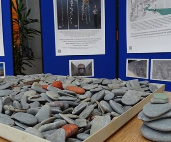 A tray of stones on a wooden table, with posters and display boards behind