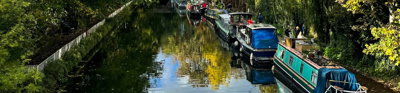 View of canal with narrow boats and autumnal trees.