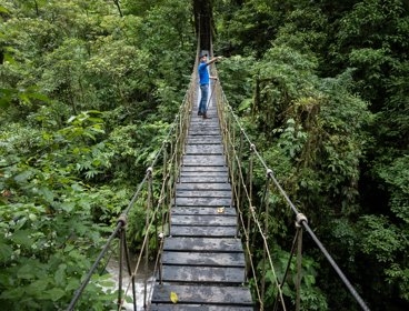A man standing on a rope bridge in the jungle