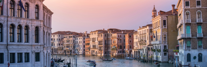 A boat sails downa cannal in in Venice as the sunsets