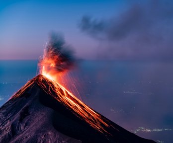 A volcano erupting with lava flowing down the sides