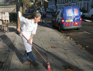 Person sweeping the pavement outside a cafe