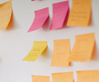 Sticky notes with writing on stuck to a wall. 