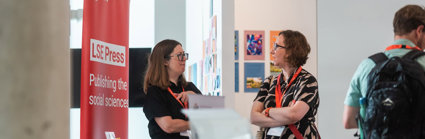 A delegate talks to a publisher's representative in the exhibitors' area