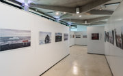 An arrangement of tall white panels displaying a photographic exhibition in a modern pavilion.