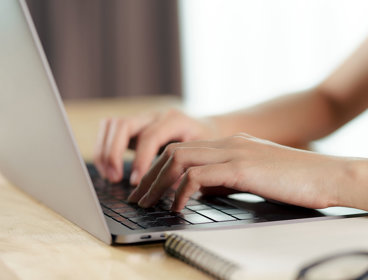 Close up of a person's hands typing on a laptop keyboard.