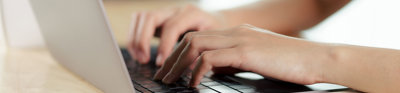 Close up of a person's hands typing on a laptop keyboard.