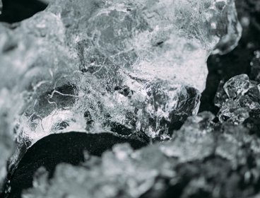 Close up photography of a stone - Ice on a black pebble