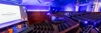 View from the balcony in the Ondaatje Theatre at the Royal Geographical Society. A presentation slide is projected on the screen and says 'Welcome to the Roayl Geographical Society'.