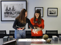 Two people beside a table looking at slides laid on a lightbox.