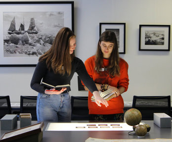 Two people beside a table looking at slides laid on a lightbox.