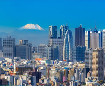 Skyline of Tokyo on a bright sunny day with in the background the snow capped top of Mount Fuji.