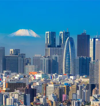 Skyline of Tokyo on a bright sunny day with in the background the snow capped top of Mount Fuji.