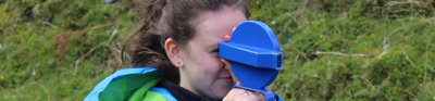 Person wearing blue rain jacket holding geographical equipment outdoors.