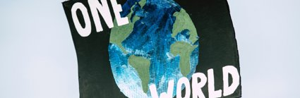 A hand-painted placard with the slogan One World and picture of a globe