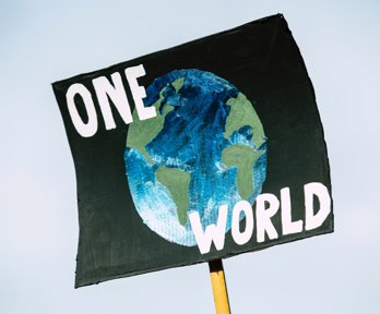 A hand-painted placard with the slogan One World and picture of a globe