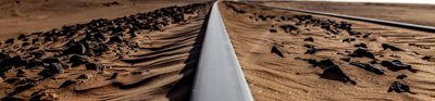 Metal train tracks run trough a rocky desert