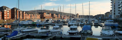 View over a harbour with white boats, red brick buildings andf blue sky