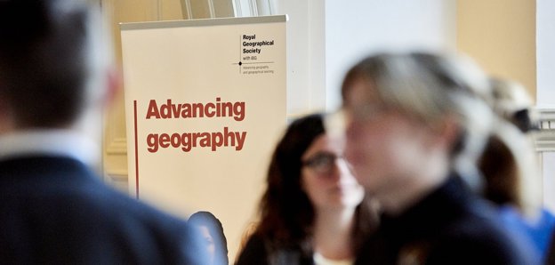 Banner with the text 'Advancing geography' and the Society's logo, with blurred figures in the foreground 
