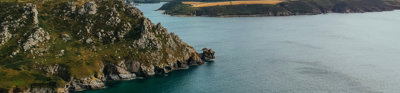 Aerial view of Devon coastline, showing rocky cliffs and green fields.