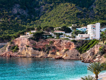 Holiday homes above a small cliff overlooking a bay with blue sea