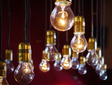 Light bulbs hanging from the ceiling with a dark red background, creating a warm ambiance.