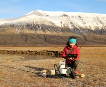 Researcher downloading data from a water monitoring station in Adventdalen.