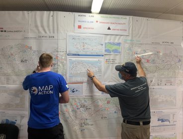 MapAction volunteer Chris Jarvis discussing maps at On Site Operations Coordination Centre for Haiti Earthquake, 2021