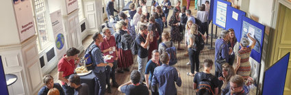 A large group of people seen from above while they are networking over tea and coffee in the main hall.