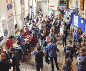 A large group of people seen from above while they are networking over tea and coffee in the main hall.