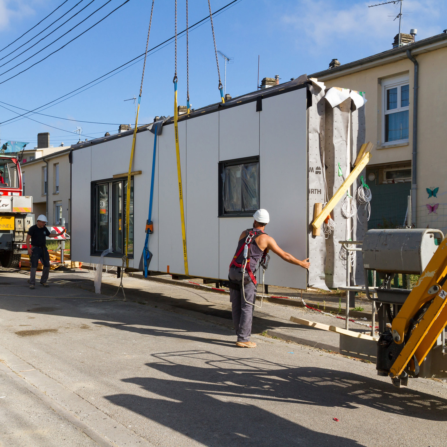 A building site showing a peice of building being lifted on a crane 