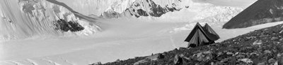 Old black and white photo of Everest with a tent in the foreground.